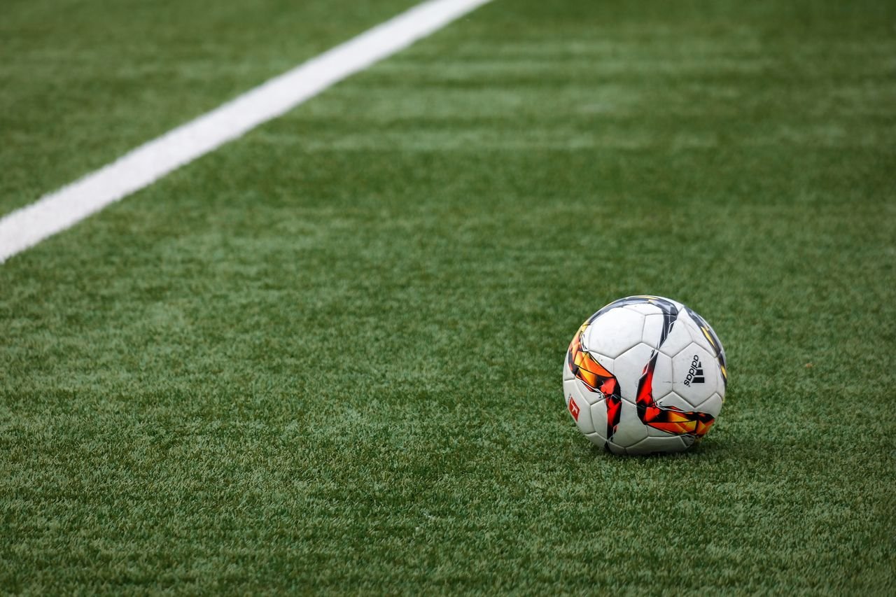 Menu A vibrant soccer ball resting on a pristine grass field beside a white sideline.