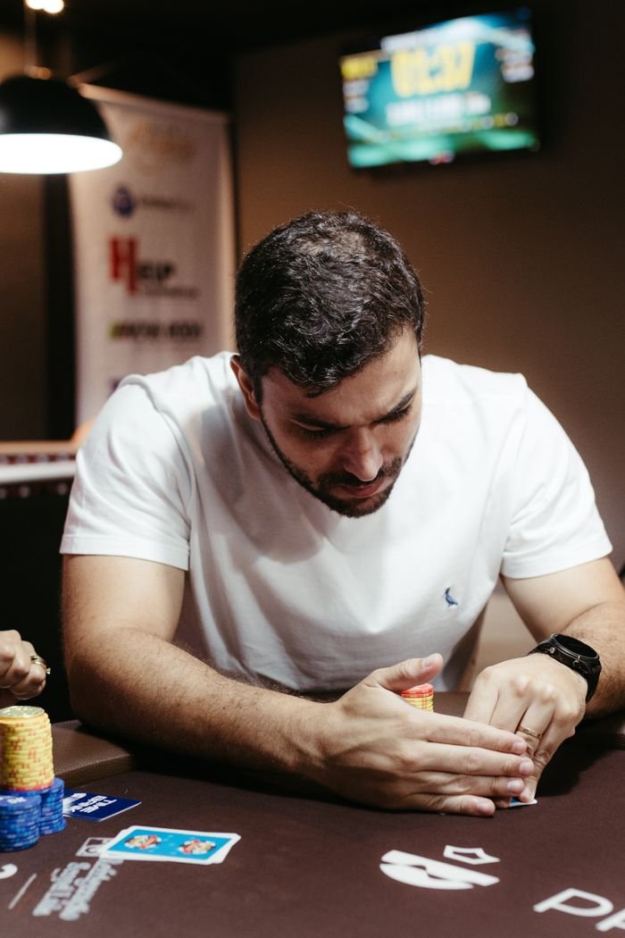 Menu Adult male intensely strategizing in a poker game with cards and chips on the table.