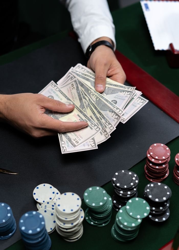 About Close-up of hands counting dollar bills on a casino table with poker chips.